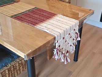Camino de mesa de algodón artesanal venezolano, colocado sobre una mesa de madera.
