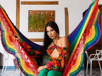 Femme installée dans un hamac à barre Pride aux couleurs arc-en-ciel