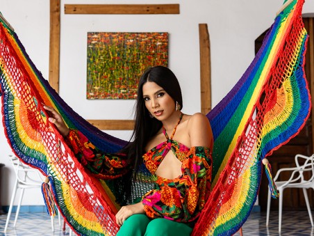 Femme installée dans un hamac à barre Pride aux couleurs arc-en-ciel